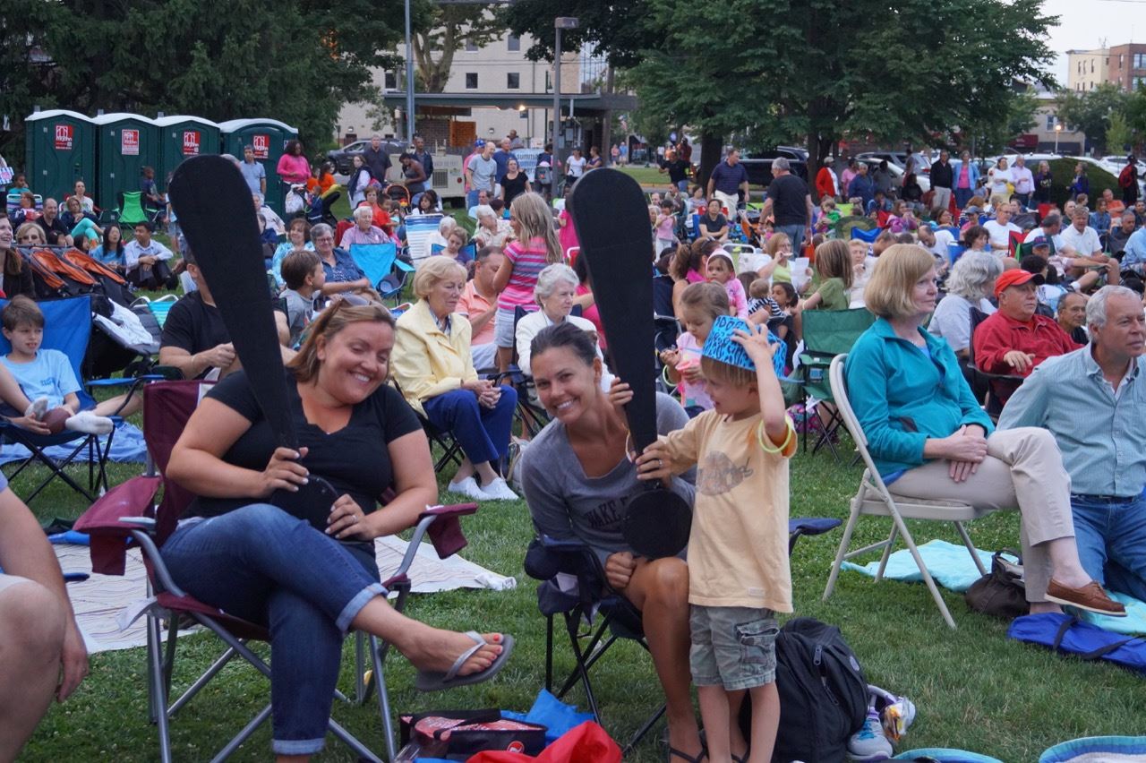 Two women of the crowd hold the Share the Fun exclamation points.